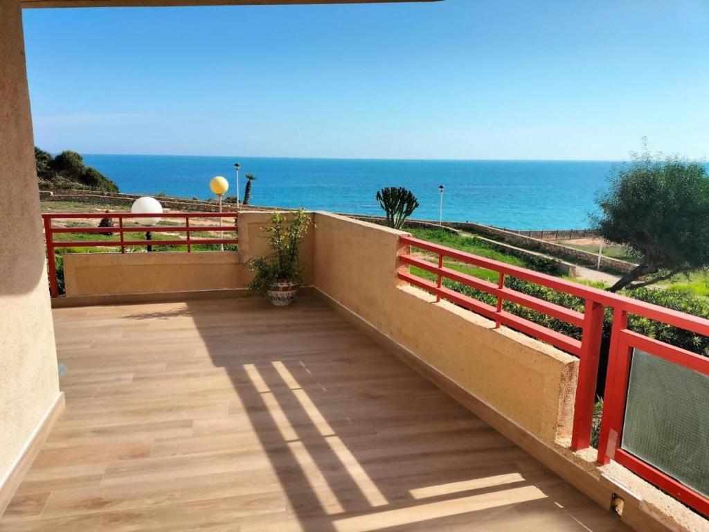 un balcón con una valla roja y vistas al océano en Vistamar apartamento B en Pilar de la Horadada