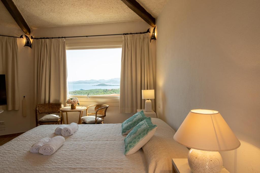 a bedroom with a bed with towels and a window at [CALA DI VOLPE] Vista Mare e Piscina in Abbiadori