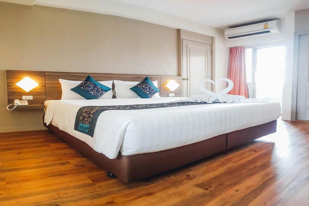a bedroom with a large white bed with blue pillows at Eastiny Inn Hotel in Pattaya