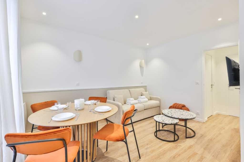 ein Wohnzimmer mit einem Tisch, Stühlen und einem Sofa in der Unterkunft Super appartement 4P 1BR Marché aux Puces in Saint-Ouen