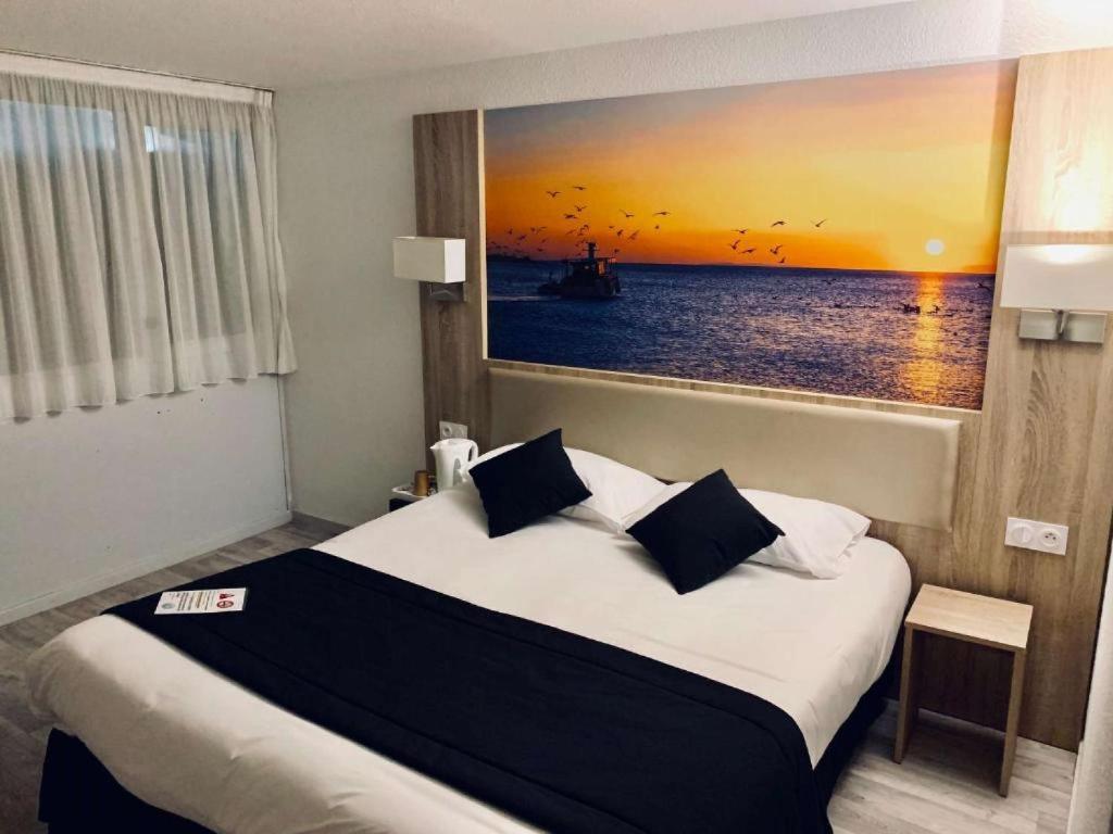 ein Schlafzimmer mit einem großen Bett und einem Gemälde an der Wand in der Unterkunft BRIT HOTEL Confort MORLAIX in Saint-Martin-des-Champs