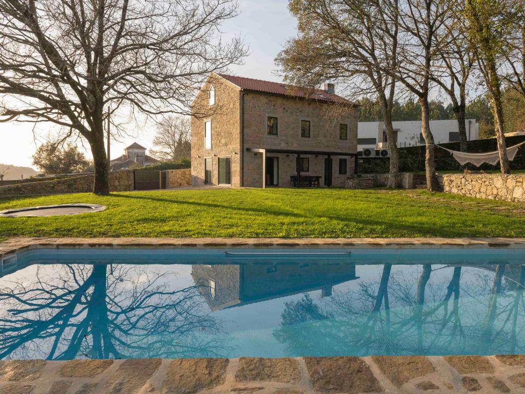 una imagen de una casa con un reflejo en una piscina en Casa Da Romeira Country House, en Freixieiro de Soutelo