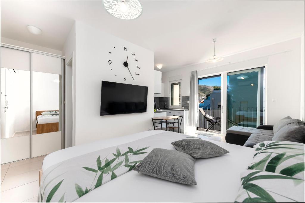 een witte slaapkamer met een groot bed met een klok aan de muur bij Apartment Marie in Dubrovnik