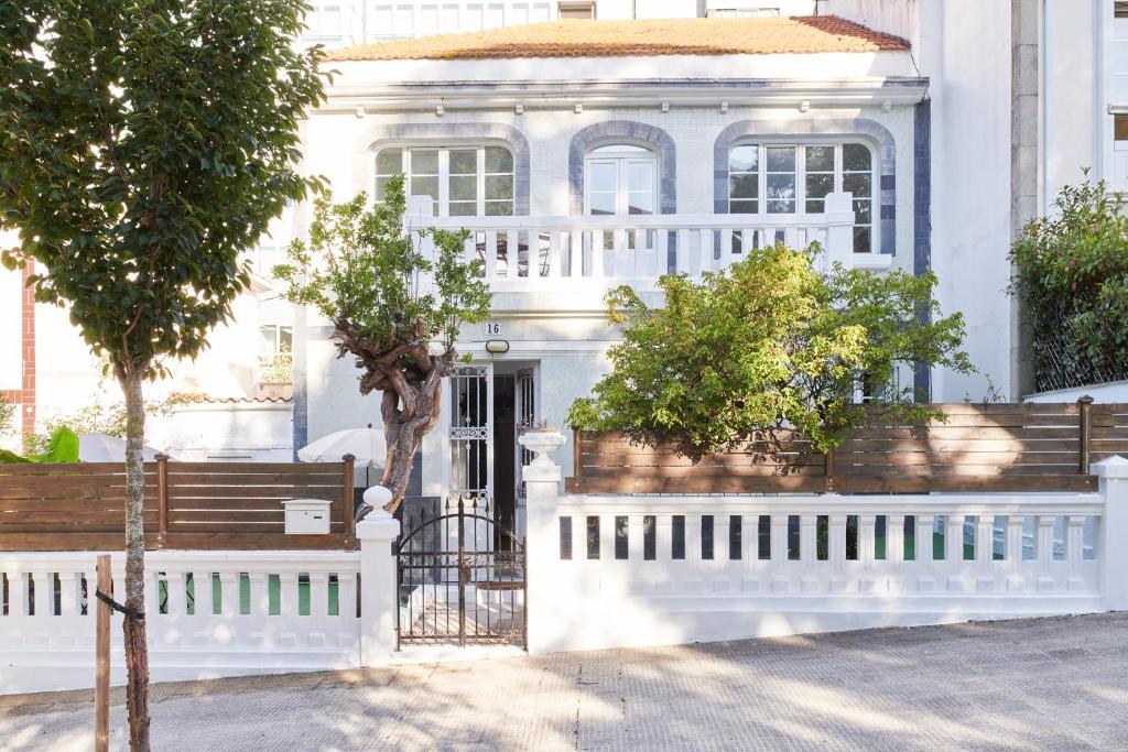 una casa blanca con una valla blanca y árboles en Adosado con jardín en el centro de A Coruña en A Coruña