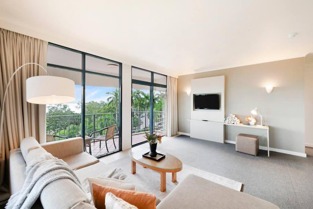 a living room with a couch and a table at Corner Balcony Suite on the Esplanade with Pool in Darwin