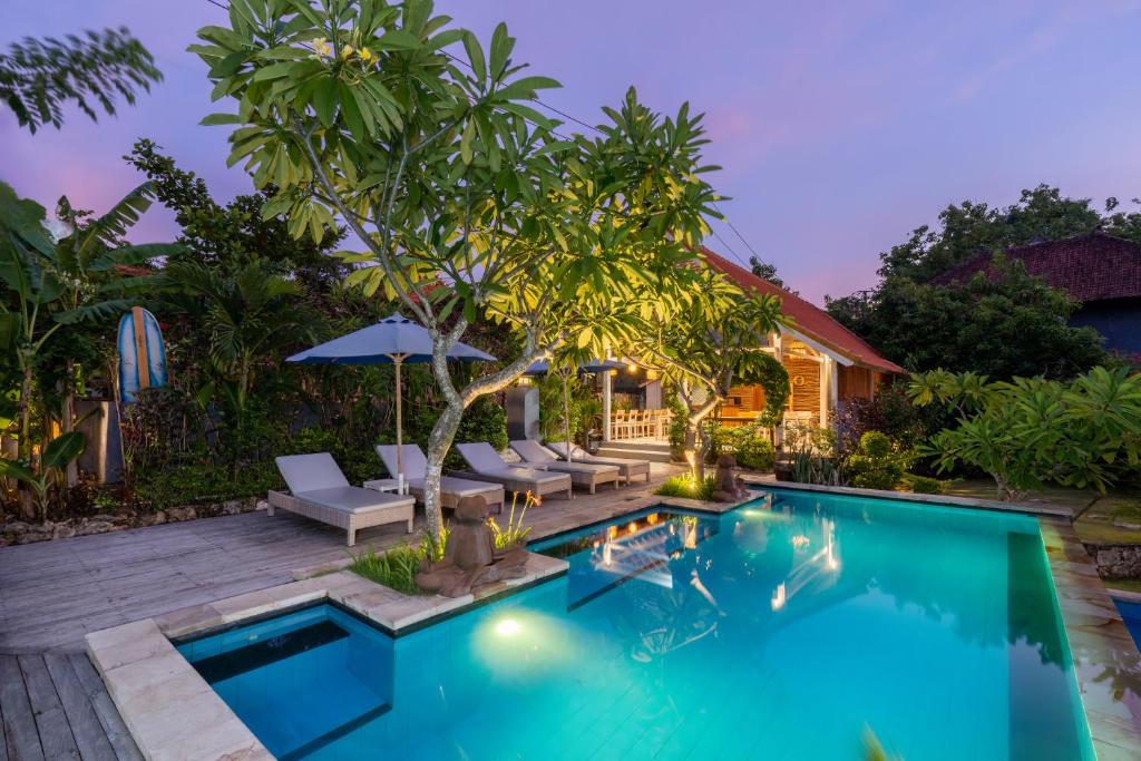 a swimming pool in a backyard with chairs and an umbrella at Le Biu garden View in Nusa Lembongan