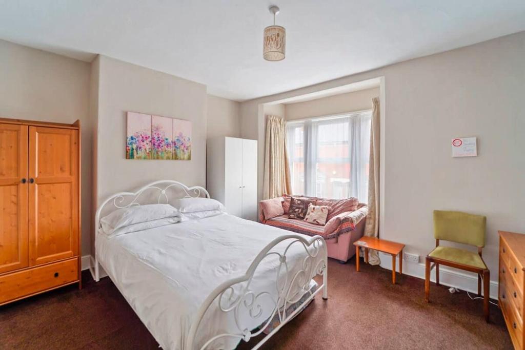a bedroom with a white bed and a chair at 4 Bed Homely Retreat - Wolverhampton in Wolverhampton