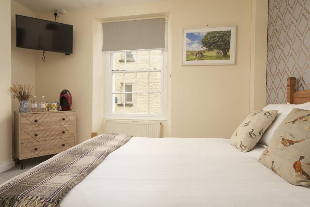 a bedroom with a white bed and a window at The White Hart Hotel in Modbury