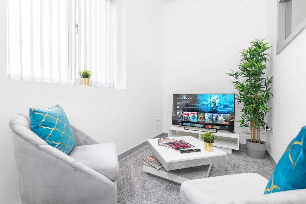 ein Wohnzimmer mit 2 Stühlen und einem Flachbild-TV in der Unterkunft Stylish Brierley Hill - 1 Bed Apt - Free Parking - Netflix & Wifi - 305O in Brettell Lane