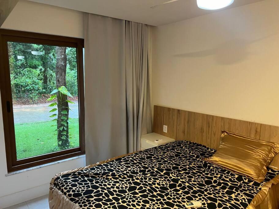 ein Schlafzimmer mit einem Bett und einem großen Fenster in der Unterkunft Casa 05 suítes, piscina e natureza in Mata de Sao Joao