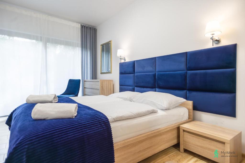 um quarto com uma cama grande e uma cabeceira azul em Apartament Gambit, Ogrody Pieniawskie, MyWeek em Polanica-Zdrój