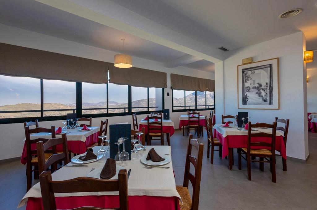 a dining room with tables and chairs and windows at Hotel Tugasa Arco de la Villa in Zahara de la Sierra