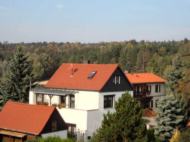 une maison blanche avec des toits rouges et des arbres dans l'établissement Ferienwohnung Am Heidesee, à Nietleben