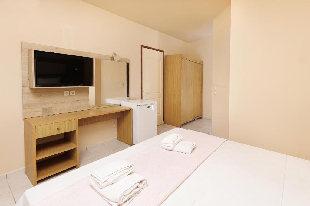a bedroom with a bed with a desk and a television at Aqua Sun Village in Hersonissos