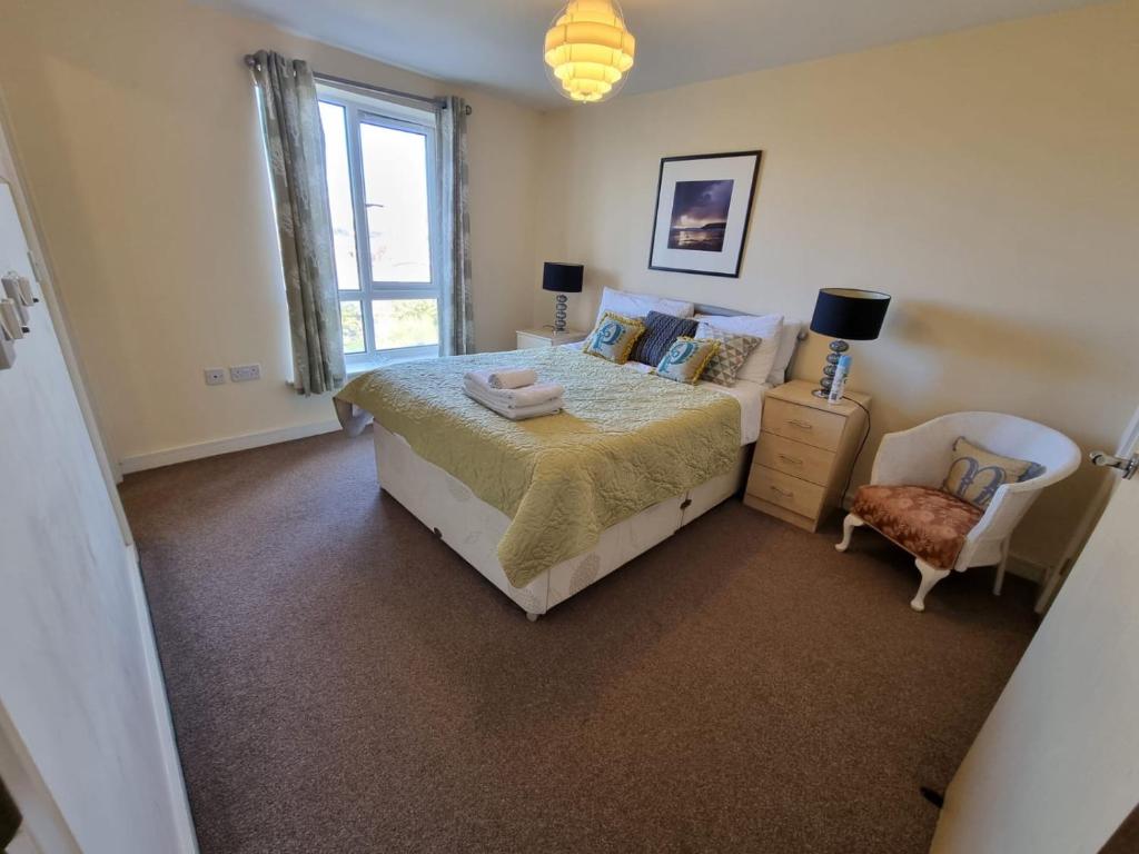 a bedroom with a bed and a chair and a window at Moonbay apartment in Cardiff