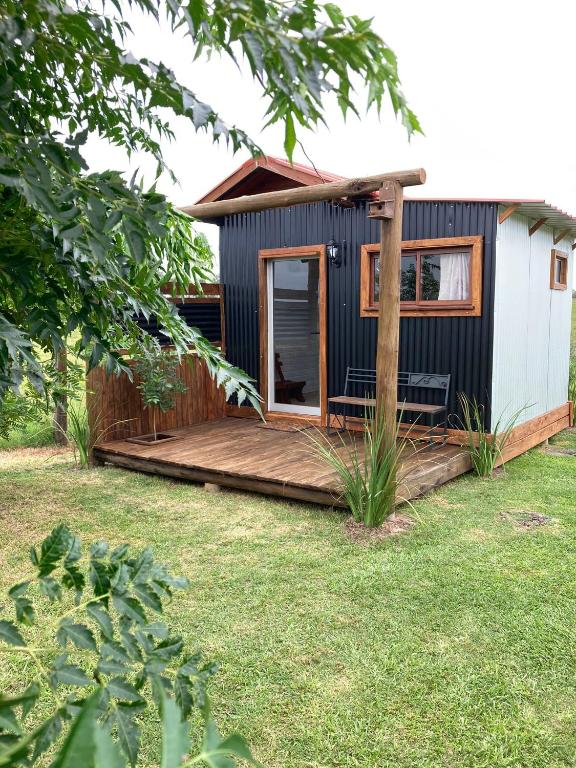 a tiny house with a deck in a yard at La Casita in Tacuarembó