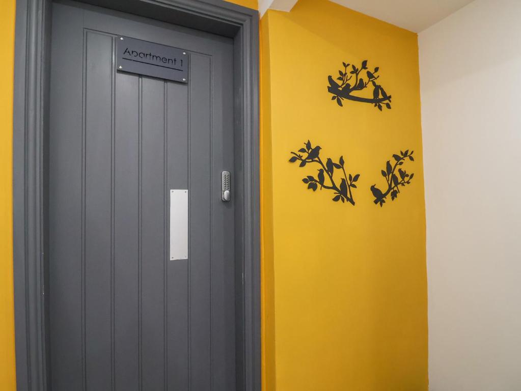 a grey door with a sign on a yellow wall at Apartment 1 in Chester