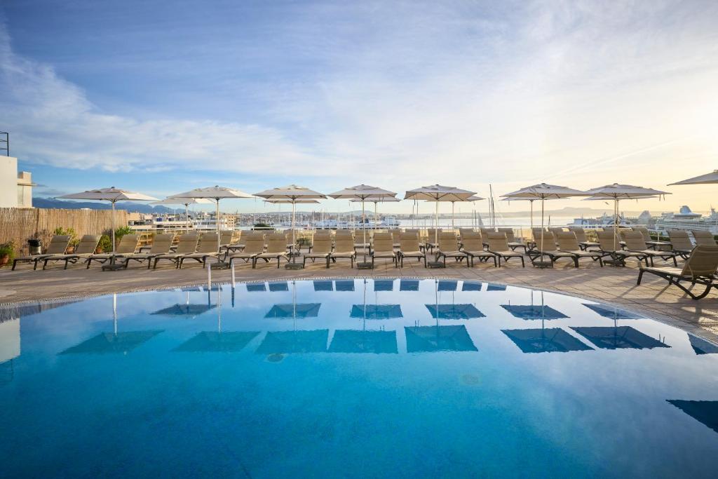 a swimming pool with chairs and umbrellas on a building at Catalonia Majórica in Palma de Mallorca