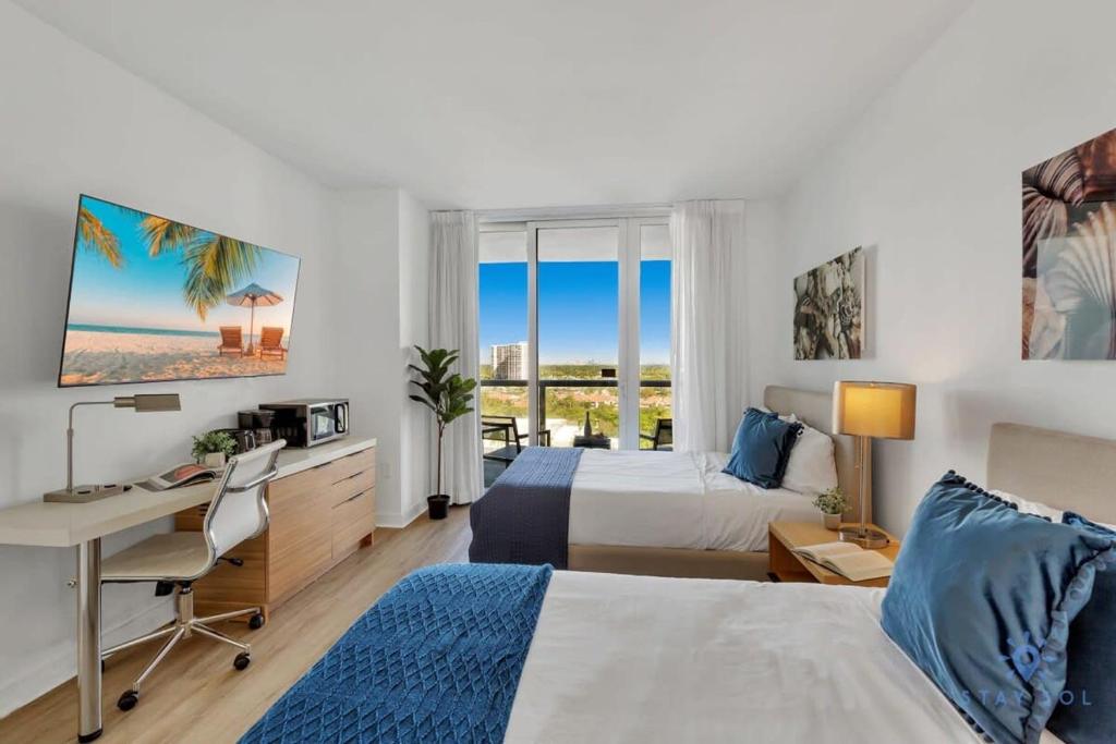 a hotel room with two beds and a desk at Infinite Views Amazing Pool Gym in Hallandale Beach