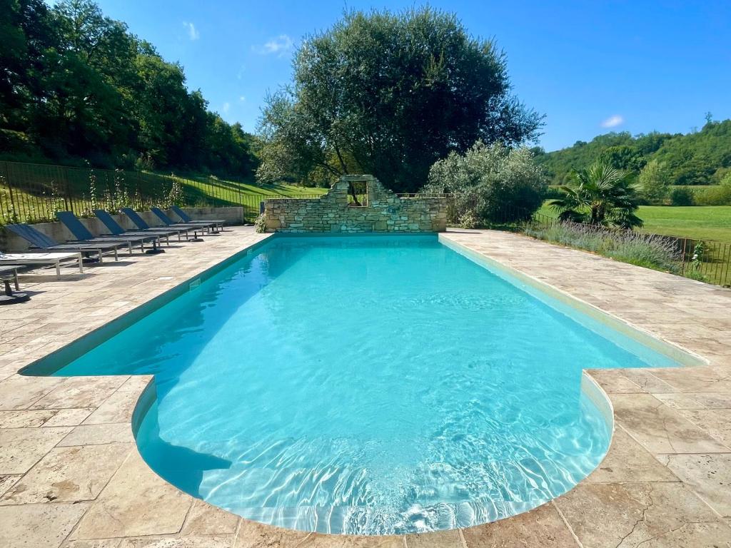 une piscine avec de l'eau bleue dans une cour dans l'établissement Le Moulin Aux Ans, à Archignac