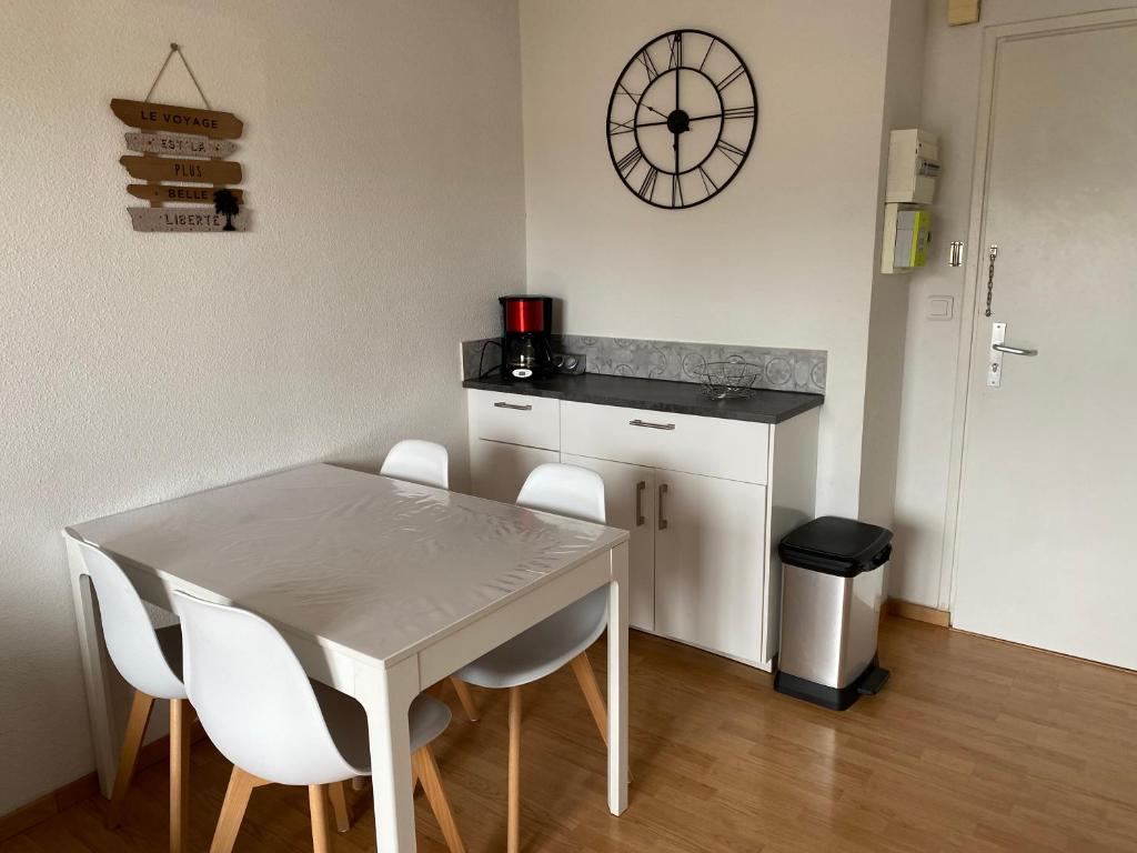 eine Küche mit einem Tisch und Stühlen sowie einer Uhr an der Wand in der Unterkunft T2, accès direct plage, proche thalasso in Cabourg