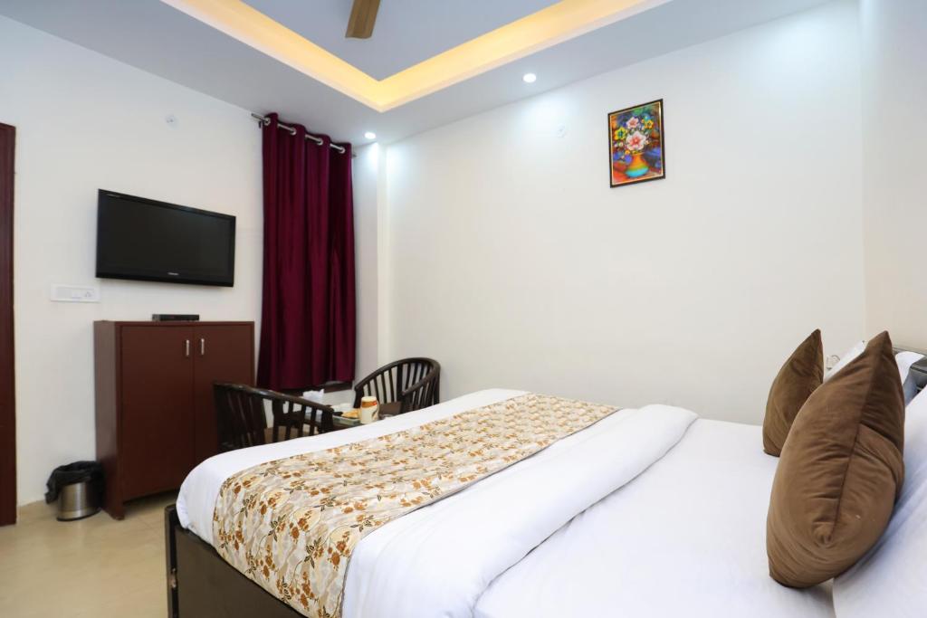 um quarto de hotel com uma cama e uma televisão de ecrã plano em Hotel Sunlight Inn em Nova Deli