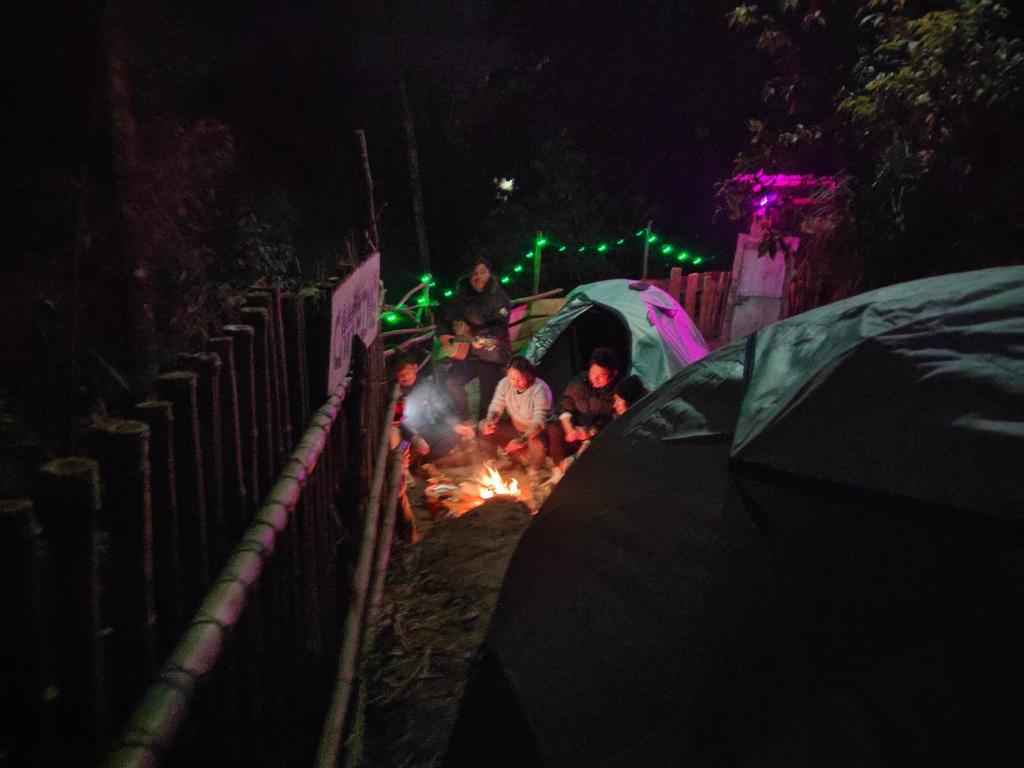 Eine Gruppe von Menschen, die im Dunkeln am Lagerfeuer sitzen in der Unterkunft Wood Locs Farm Stay & Campsite in Darjeeling