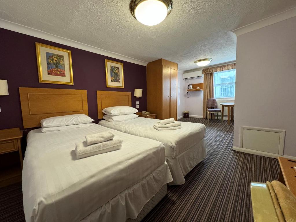 a hotel room with two beds with towels on them at The Chatsworth Hotel in Worthing