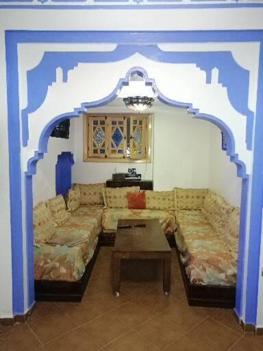 uma sala de estar com um sofá e uma mesa em Dar issam em Chefchaouen