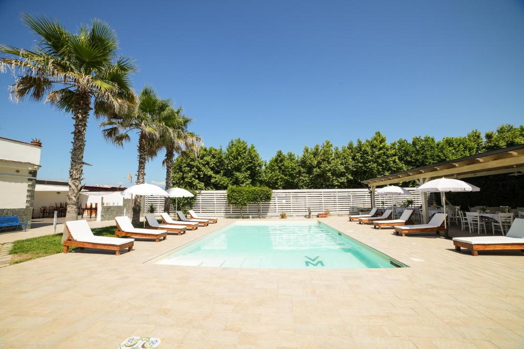 een zwembad met ligstoelen en palmbomen bij Villa Miramare in Pontecagnano
