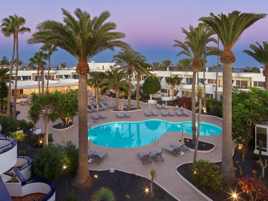 - une vue aérienne sur un complexe avec une piscine et des palmiers dans l'établissement H10 Ocean Dunas - Adults Only, à Corralejo