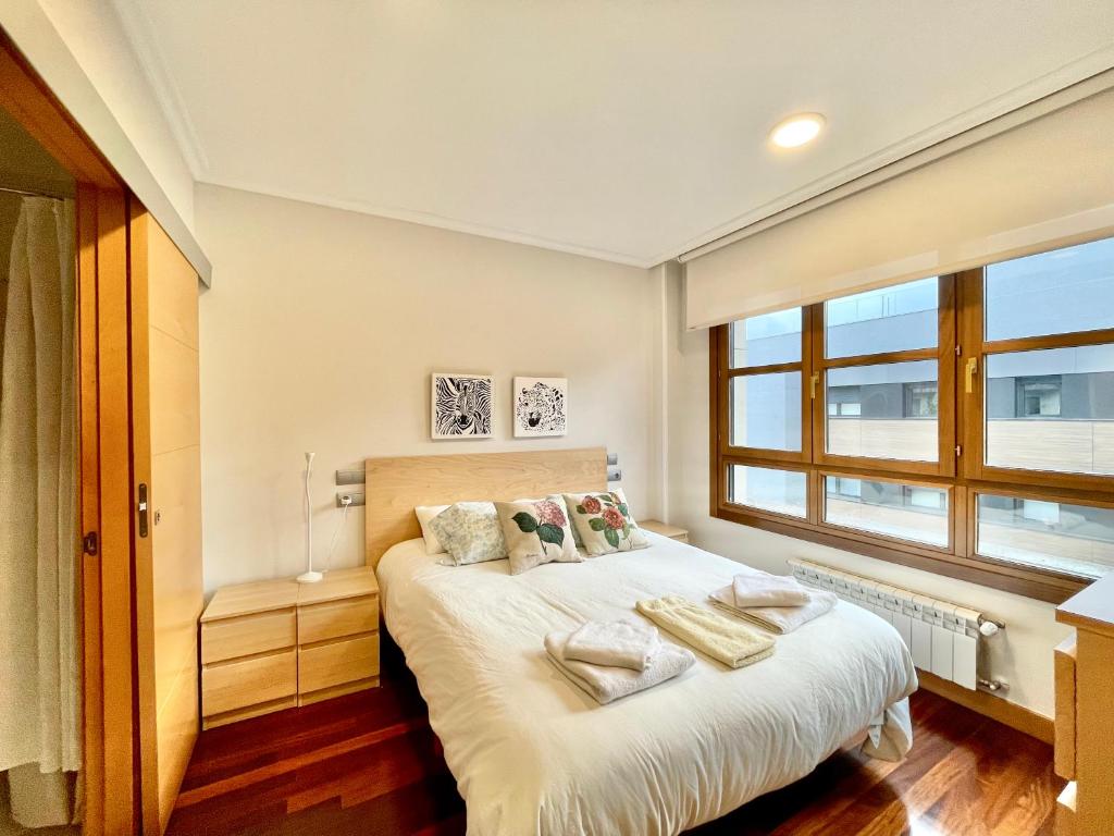 1 dormitorio con 1 cama con sábanas blancas y ventana en Apartamento con piscina VIESQUES, en Gijón