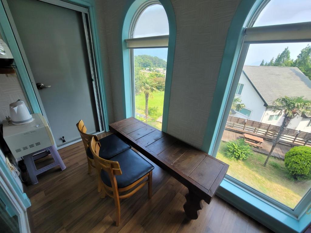 a room with a wooden table and a large window at Santa Monica Pension in Kokhae