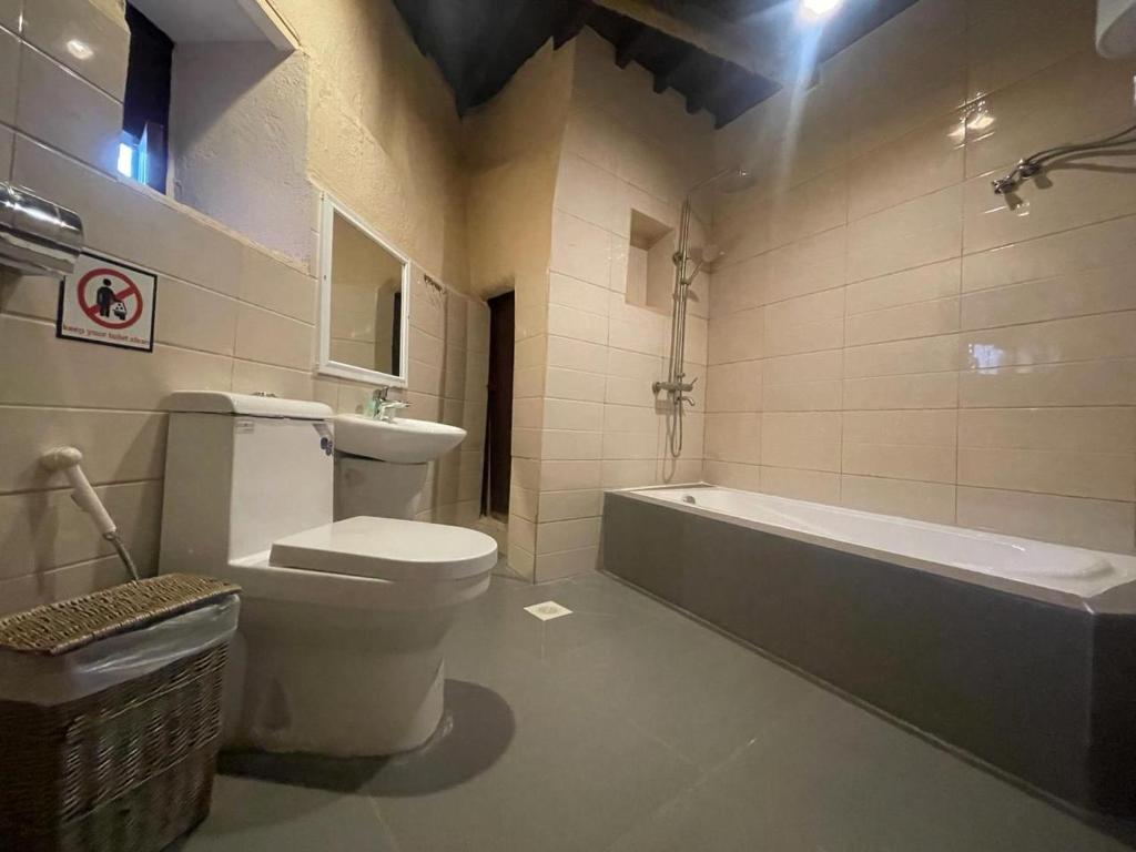 a bathroom with a toilet and a bath tub at The traditional house in Nizwa