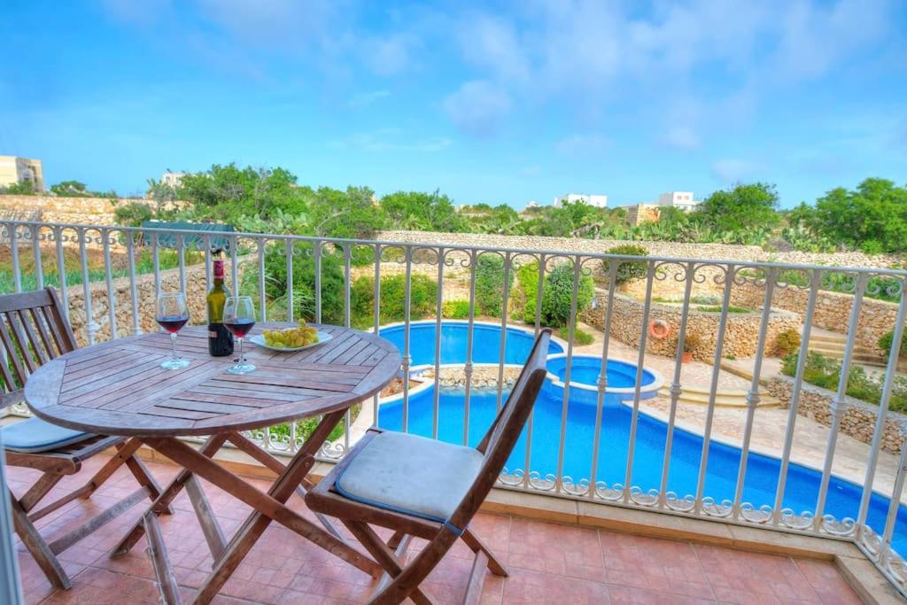 einen Tisch und Stühle auf einem Balkon mit Pool in der Unterkunft A lovely 3BR spacious home with Access to POOL by 360 Estates in Qala