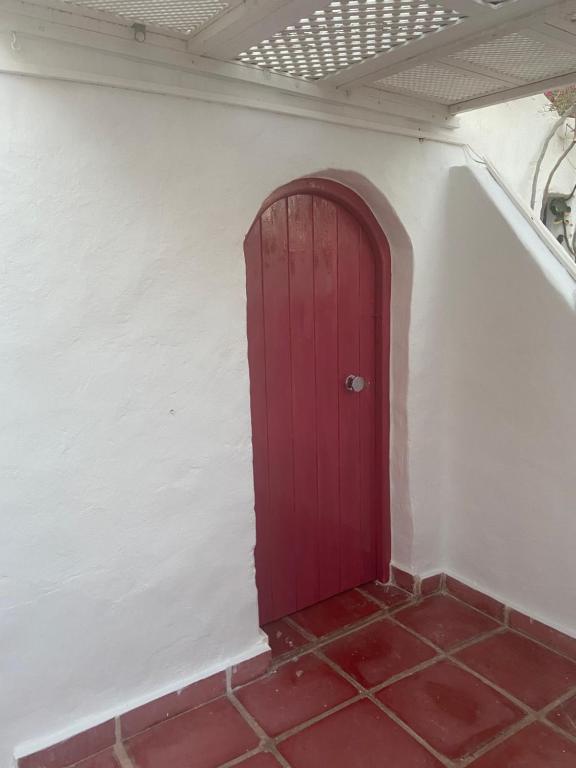 a red door in a white wall with a red tile floor at RESIDENCE DAR YASMINa in Mezraya
