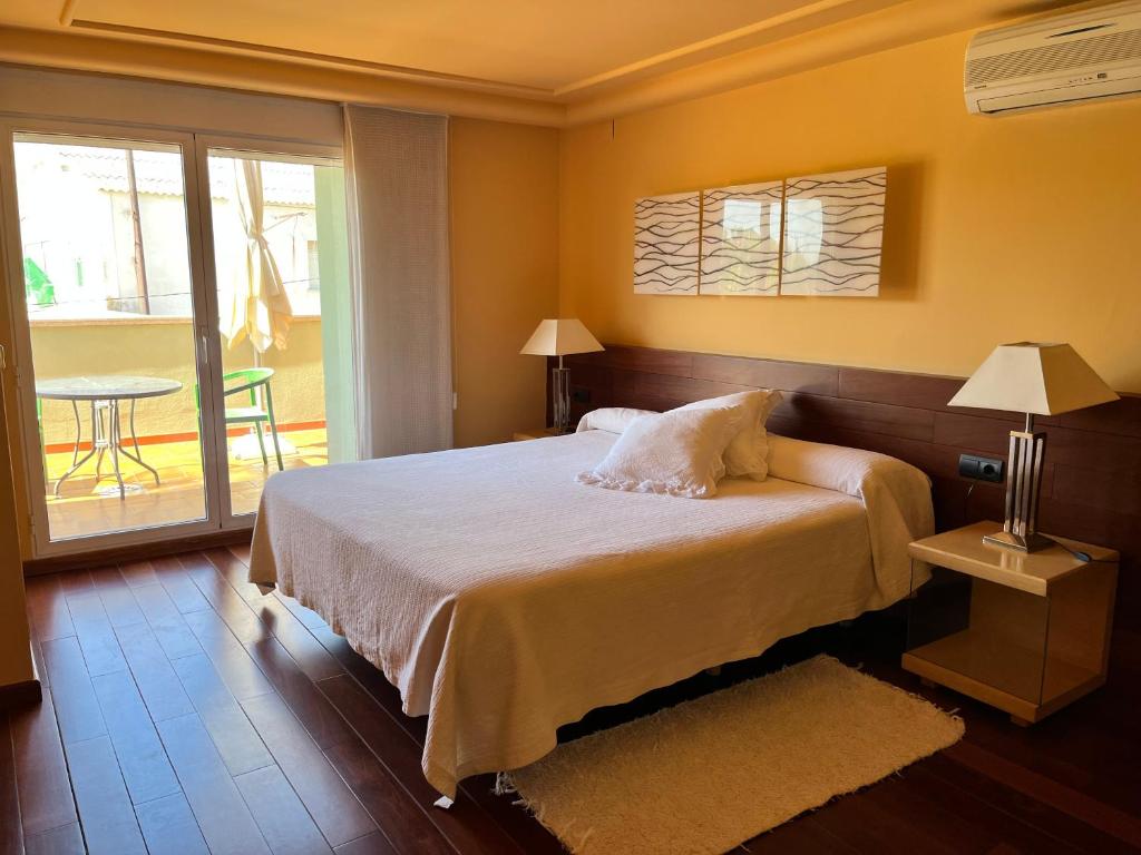 a bedroom with a bed and a balcony with a table at PENSIÓN EL CARRO in Utiel