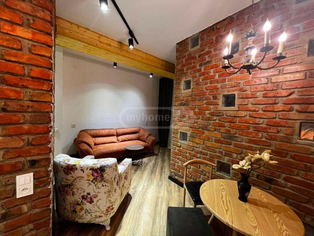 ein Wohnzimmer mit Sofa und Ziegelwand in der Unterkunft Apartment in Tbilisi Dadiani 3 in Tbilisi City