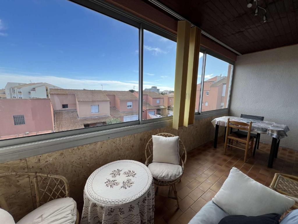 um quarto com uma grande janela com uma mesa e cadeiras em Appartement Valras-Plage, 2 pièces, 3 personnes - FR-1-701-67 em Valras-Plage