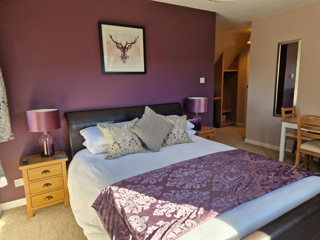 a bedroom with a large bed with purple walls at Croft 17 in Ullapool