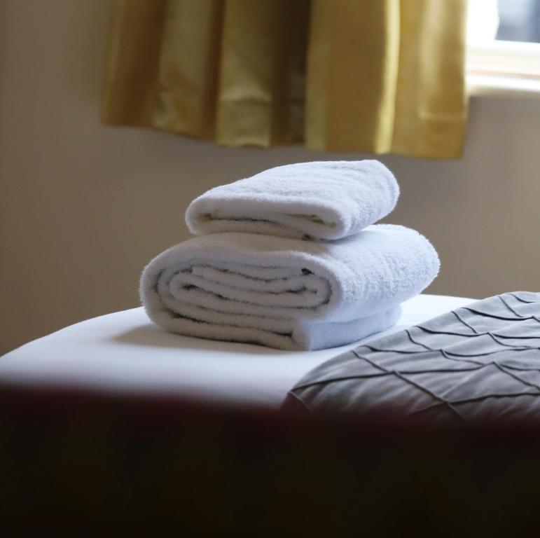 a pile of towels sitting on top of a bed at The George Inn in Windsor