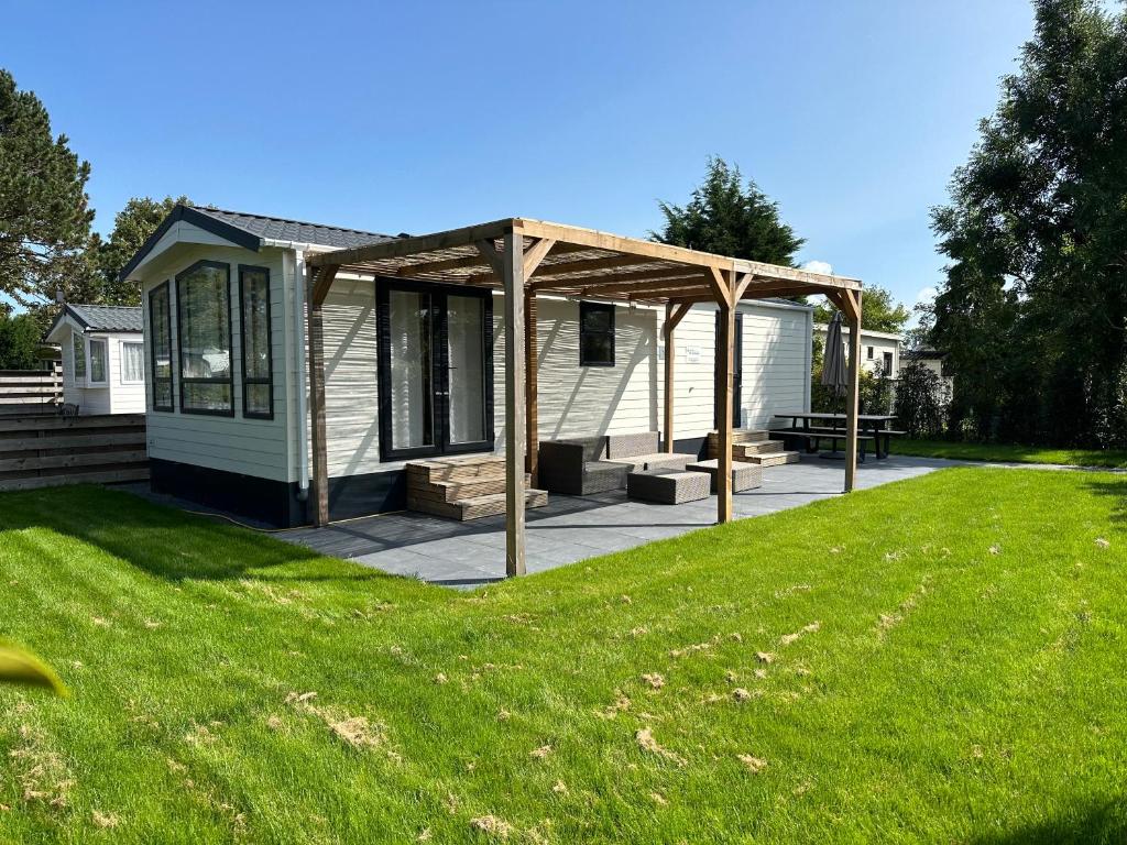 a house with a pergola in a yard at Chalet 527 op Recreatiepark De Wielen in Sint Maarten