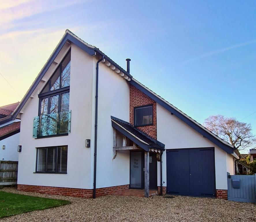 a white house with a black garage at Tree Top View Sheringham - Reverse Living - EV Charger - Quirky in Sheringham