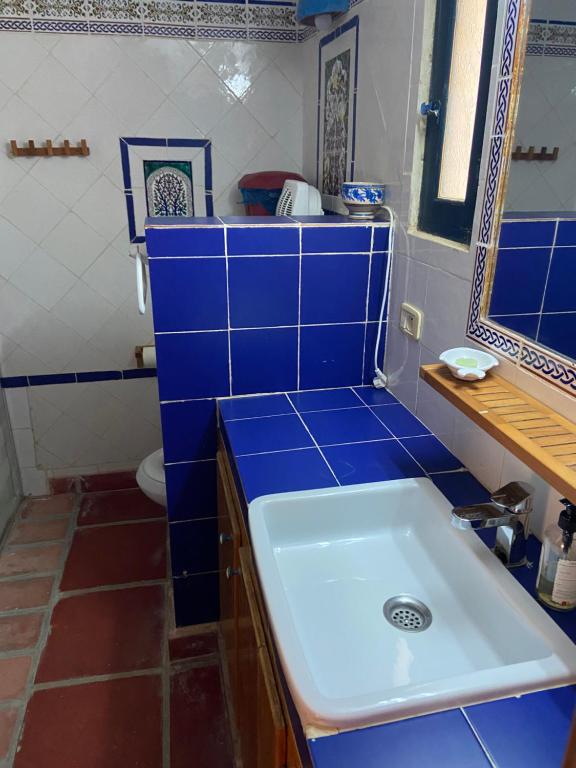 a blue tiled bathroom with a sink and a toilet at RESIDENCE DAR YASMINa in Mezraya