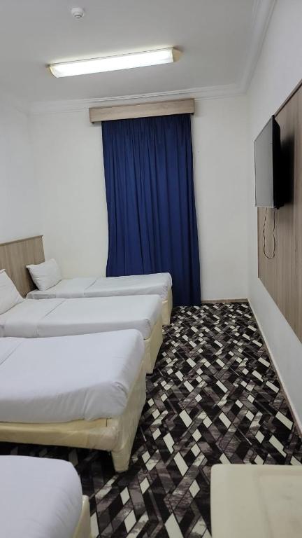 um quarto com três camas e uma cortina azul em منازل المنال em Meca