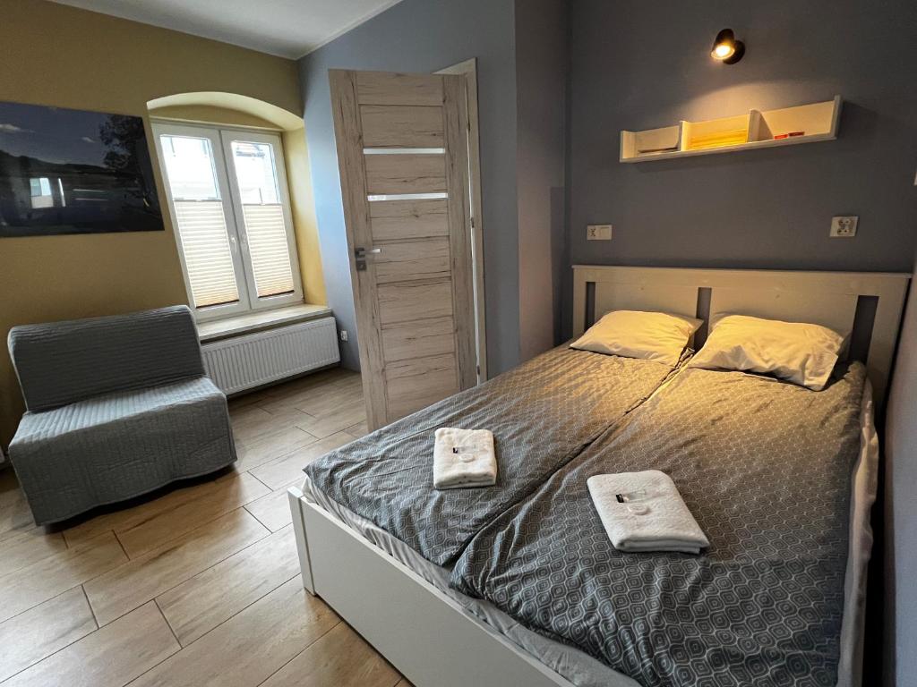 a bedroom with a bed and a chair and a window at Apartament MRĄGOWIA in Mrągowo