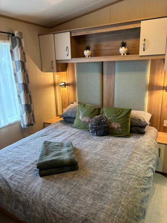 1 dormitorio con 1 cama grande con almohadas verdes en Woodpecker lodge, Camelot Holiday Park, CA6 5SZ en Carlisle