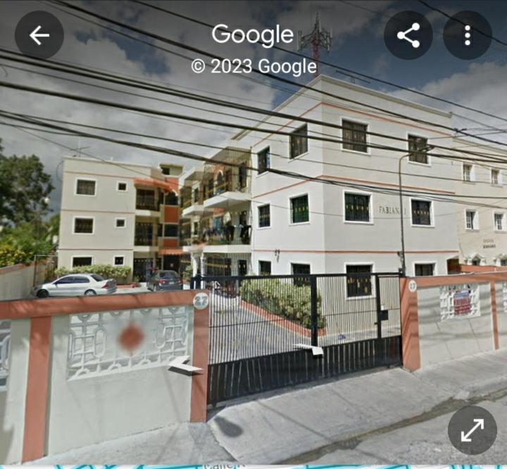 - Vistas a un edificio blanco con una valla en Clásico apartamento en Santo Domingo Este, en El Seis