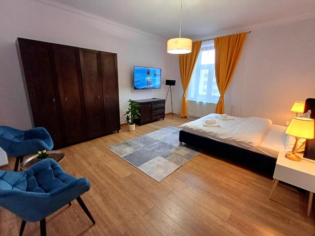 a bedroom with a bed and two blue chairs at Bella Casa - ApartHotel in Dej