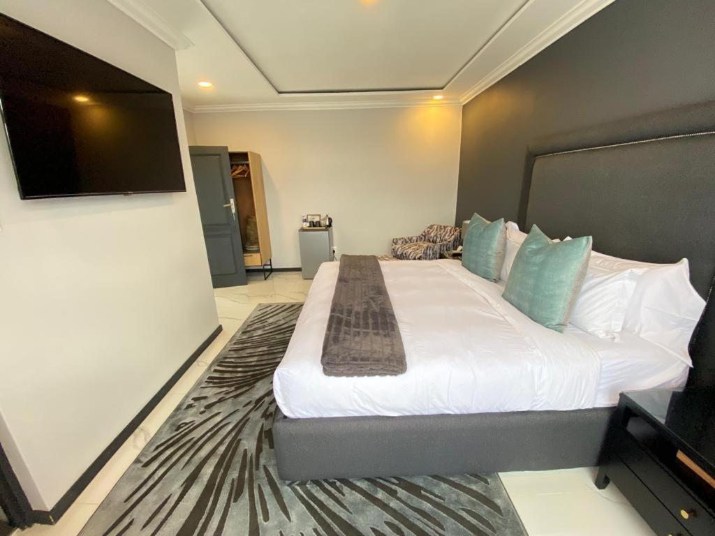a bedroom with a large bed with a flat screen tv at Luxurious Mangethe Suite - 2206 in Bulawayo